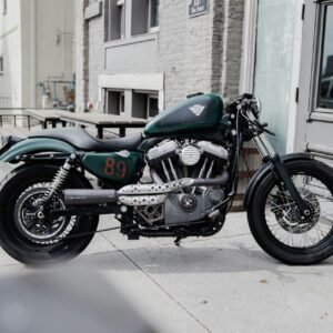 blue and black standard motorcycle parked beside brown concrete building during daytime